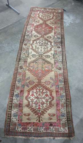 Cream ground runner with five interlocking central hooked medallions, with foliate decoration,