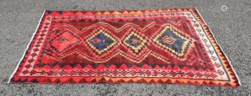 Eastern rug, red ground with four stepped lozenge shaped medallions in red, oranges, blues and pinks