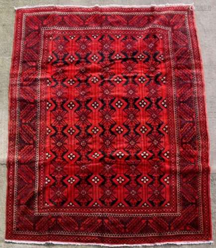 A Persian Balouch woollen handmade rug with geometric design on a red ground, 297 by 200cms (117
