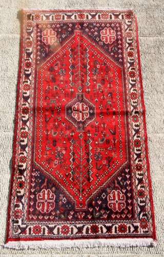 A Persian Shiraz woollen hand knotted rug with central gul decoration within a stylised floral