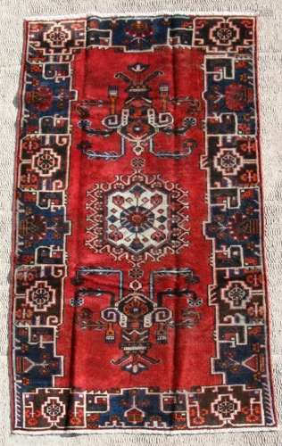 A Persian Baluch woollen hand knotted rug with stylised design on a beige ground, 239 by 178cms (