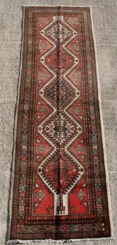A Persian Tabriz woollen hand knotted runner with central guls within a stylised border, on a