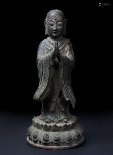 Bronze figure of a standing shaven headed priest Chinese, late Ming in prayer pose, dressed in