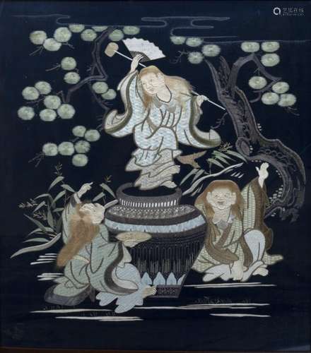 Embroidered black silk panel, Chinese, depicting figures dancing around a cauldron beneath pine