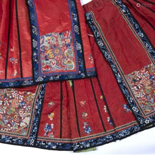 Two red silk lady's skirts each with Peking and other embroidered designs and banding
