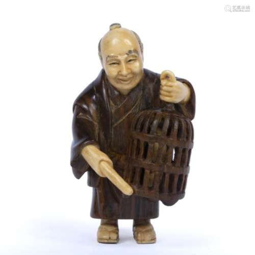 Boxwood and ivory netsuke Japanese, early 20th Century in the form of a figure holding a cage