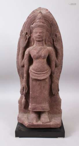 A 12TH CENTURY STYLE CAMBODIAN KHMER STYLE RED SANDSTONE CARVING OF A FOUR-ARMED DEITY. 52cms high.