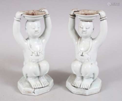 PAIR OF CHINESE BLANC DE CHINE PORCELAIN CANDLESTICKS OF BOYS, in a seated position holding a tray