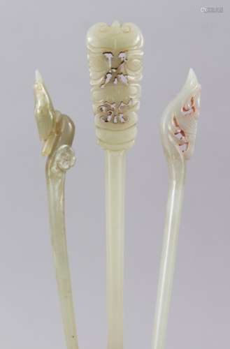 THREE 19TH / 20TH CENTURY CHINESE CARVED JADE HAIR PINS, each with a carved top, 19.5cm, 16cm & 15.