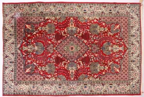 A PERSIAN ISFAHAN CARPET, red ground with central medallion, urns of flowers in a conforming