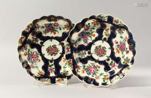 A PAIR OF WORCESTER BLUE SCALE PLATES, finely painted with colourful flowers in gilt panels, fretted