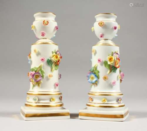 A PAIR OF SMALL MEISSEN CANDLESTICKS, with floral encrusted decoration, on square bases, crossed