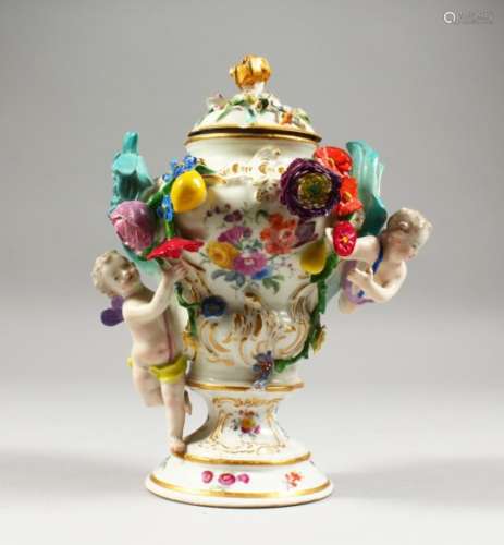 A MEISSEN PEDESTAL VASE AND COVER, decorated with cherubs and floral swags. 8ins high.