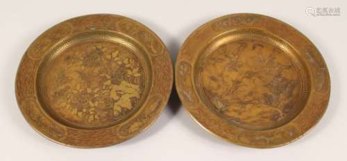A PAIR OF BRASS CIRCULAR DISHES, engraved with birds amongst trees. 9.5ins diameter.