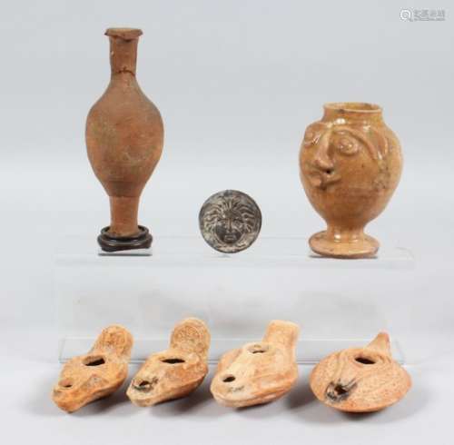 FOUR ROMAN TERRACOTTA OIL LAMPS, a small amphora style bottle, a figural pedestal jar and a
