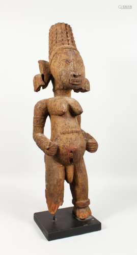 A LARGE CARVED WOOD AND PAINTED TRIBAL FIGURE, of a standing female, on a later base. 31ins high.