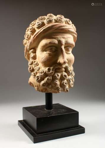 A GREEK STONE BUST OF ZEUS, on a wooden base. Bust: 11ins high.