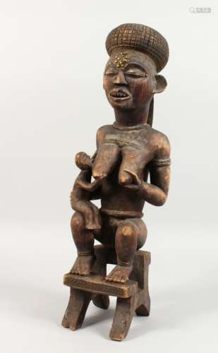 A LARGE CARVED WOOD TRIBAL FIGURE, mother and child seated on a stool. 21.5ins high.