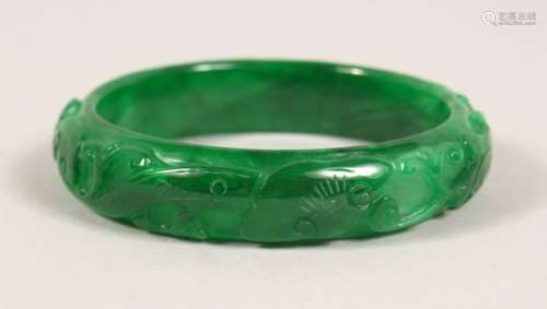 A CARVED APPLE GREEN JADE BANGLE. 3ins diameter.