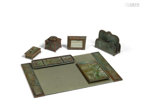 Seven Piece Pine Needle Desk Setcirca 1910patinated bronze, Favrile glass, comprising calendar frame, letter holder, pair of blotter ends and pad, inkwell, stamp holder, pen tray and notepad holder, each element stamped 'TIFFANY STUDIOS NEW YORK' with various numbers, inkwell apparently unnumberedheight of letter holder 5 1/4in (13.3cm); width 6 1/4in (15.8cm); depth 2 3/4in (6.9cm)  Tiffany Studios (1899-1930)