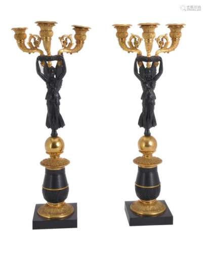 A pair of patinated and parcel gilt metal three light figural candelabra in Empire style