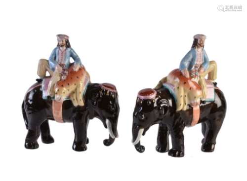 A pair of Staffordshire pottery caparisoned elephants with mahout and tiger of William Kent type