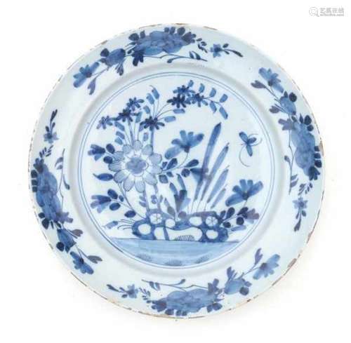 A Delftware blue and white charger, decorated with flowers in a rocky garden. 18th centuryDiameter