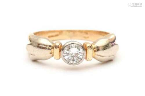 A 14 carat yellow and white gold solitaire ring flanked by flowers. Set with a brilliant cut