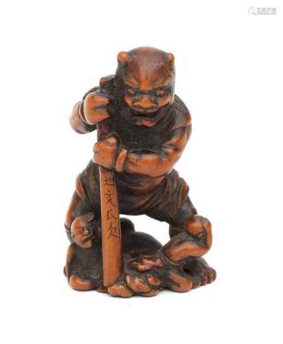 A boxwood netsuke, Oni holding a staff with characters, dressed in animal hides, three human figures