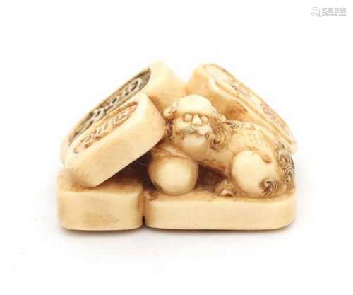 A Japanese ivory netsuke in the shape of three seals and a shishi with ball. Meiji period (1868-