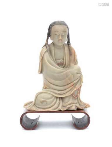 A soapstone sculpture of a seated young lady, with prayer beads in her hands.Her hair, lips and