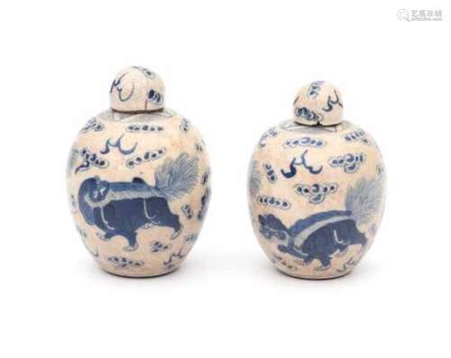 A pair of Chinese blue and white softpaste lidded jarlets, decorated with foo dogs. Marked with