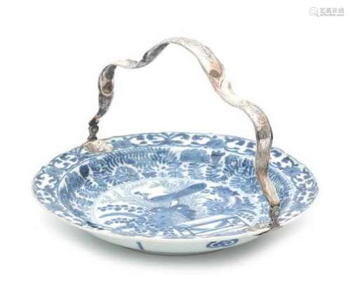 A Chinese blue and white dish with silver handle. Decorated with a peacock in a garden. With