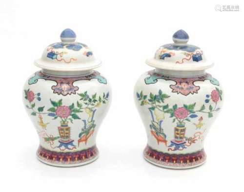 A pair of Chinese famille rose lidded vases, decorated with precious objects and flowers. With