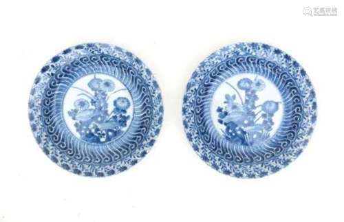 A pair of Chinese modelled blue and white plates, decorated with flowers in a rocky garden. with a