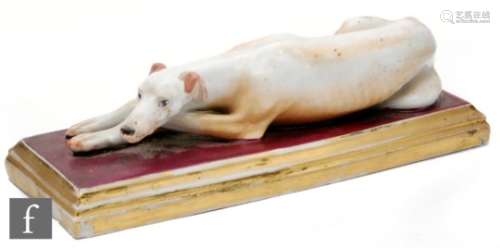 A 19th Century continental porcelain figure of a recumbent greyhound glazed in tan and white, on a