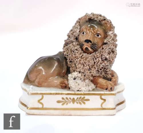 A 19th Century Staffordshire figure of a lion and lamb, the recumbent lion and lamb mounted on a