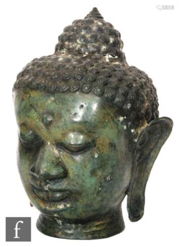 A Tibetan or Burmese cast metal figure of a Shakyamuni Buddha head with downcast eyes and
