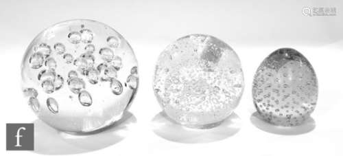 A collection of three large contemporary glass paperweights, each clear with internal controlled air