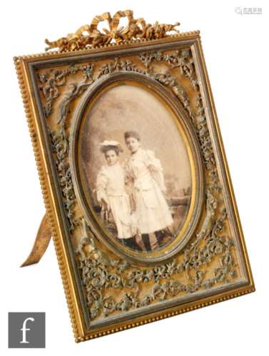 A late 19th Century French brass photo frame mounted with a bow above a border of winged angelic