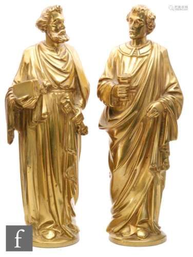 A pair of gilt metal figures of apostles each dressed in a classical flowing robe, one holding a