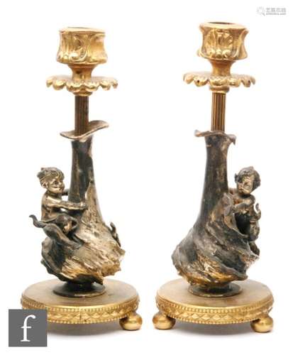 A pair of early 20th Century French gilt and plated candlesticks, the sticks modelled in the