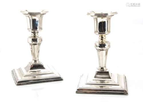 A pair of Edwardian silver filled candlesticks, square base with short stems and integrated