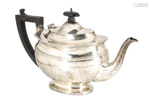 A George V silver teapot from C.S. Harris & Sons Ltd, oval on spreading foot, with applied black