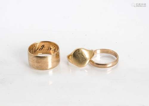 Three 18ct gold rings, comprising a child's signet ring (af) and two wedding bands, ring size N