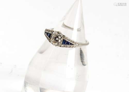 An Art Deco sapphire and diamond dress ring, the central cushion cut diamond flanked by pave set