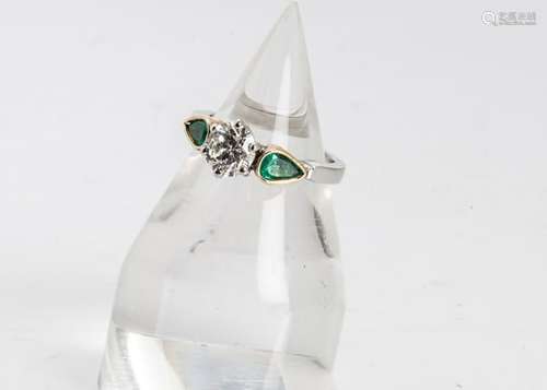 A three stone emerald and diamond dress ring, the central brilliant cut diamond in six claw