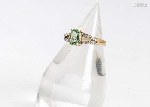 An 18ct gold peridot and diamond dress ring, the oval claw set central peridot with bifurcated