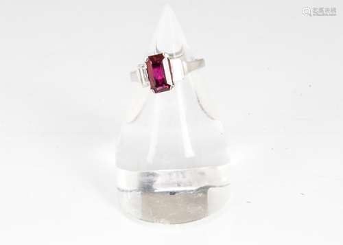 A ruby and diamond three stone ring, in the Art Deco style, the rectangular cut ruby flanked by a