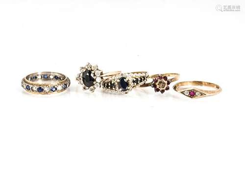 A collection of five gem set dress rings, including a sapphire example, a three stone ruby and